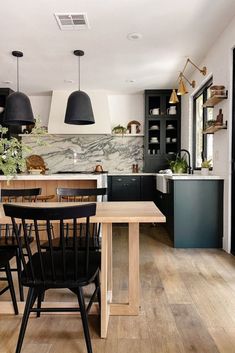 an image of a kitchen with black cabinets and wood flooring on the side wall