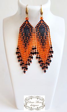 an orange and black beaded earrings on a white mannequin