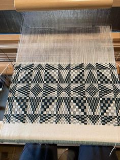 someone is working on a weaving machine with black and white checkerboard pattern in the background