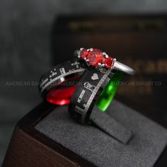 two wedding rings with crosses and red stones on each ring are sitting on top of a box