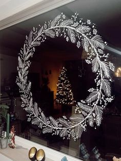 a christmas wreath is drawn on the window sill in front of a decorated tree