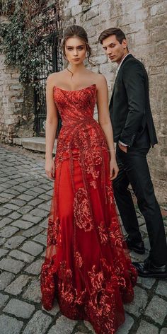 a woman in a red dress standing next to a man