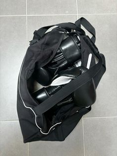 a black duffel bag filled with shoes and headphones