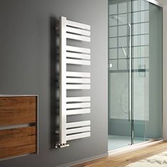 a bathroom with a glass shower and wooden flooring next to a white towel rack