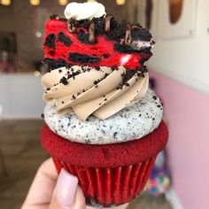 a red velvet cupcake with white frosting and chocolate sprinkles on top