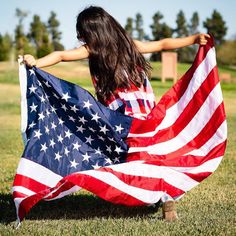 a girl holding an american flag in the grass