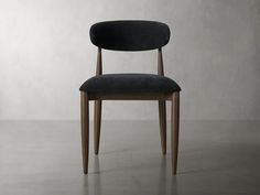 a black chair sitting on top of a floor next to a white wall with a wooden frame