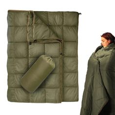 a woman standing next to a sleeping bag and an army green blanket with a roll on it