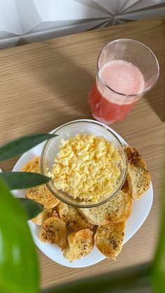 there is a plate with food on it next to a glass of juice and some bread