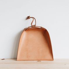 a brown leather purse sitting on top of a wooden table next to a white wall