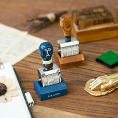 some stamps are sitting on a table next to an open book and a stamp pad