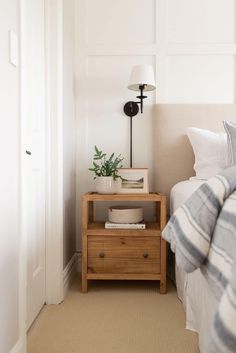 a bedroom with a bed, nightstand and plant on the night stand next to it