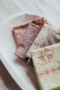 four napkins sitting on top of a white plate covered in different colored fabric designs