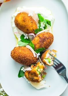 a white plate topped with fried food and a fork next to it on a table