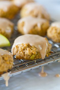 some food is sitting on a cooling rack with icing and apples in the background