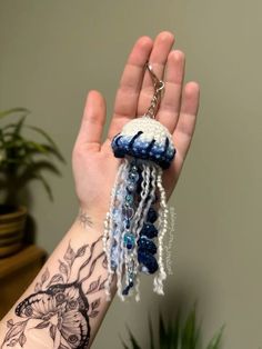 a hand holding a blue and white beaded jelly keychain in it's palm