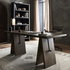 a wooden desk sitting on top of a rug in front of a book shelf filled with books