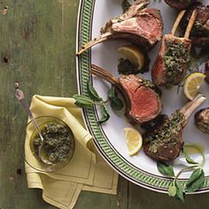 a white plate topped with lamb chops and lemon wedges