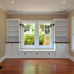 an empty room with white bookcases and wood floors