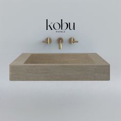 a bathroom sink with two faucets on the wall and kobu logo above it