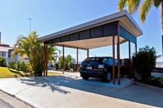 a car is parked in front of a carport with palm trees on the side