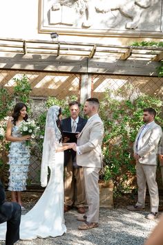 a bride and groom are getting married in front of an outdoor gazebo with greenery