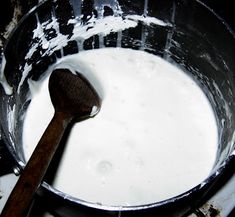 a wooden spoon in a metal pan filled with milk