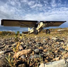 an airplane sitting on top of a rocky field