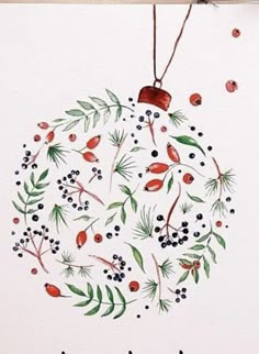 a christmas ornament with berries and leaves hanging from a string on a white wall