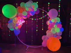 an arch made out of balloons and streamers at a birthday party with neon lights