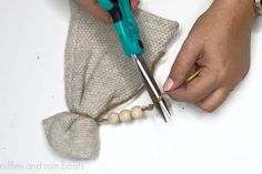 someone is cutting fabric with scissors on a white surface and some beads are in the background