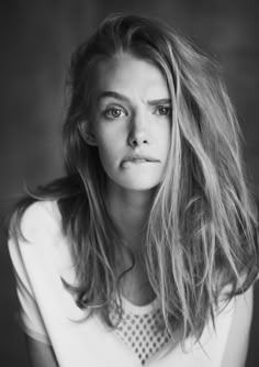 a black and white photo of a young woman with long hair looking at the camera