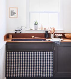 a kitchen sink sitting under a window next to a counter with utensils on it