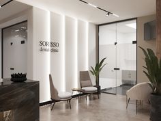 an office lobby with chairs and plants in the corner, along with signage on the wall