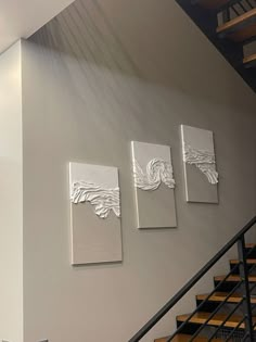 three paintings hang on the wall next to stairs