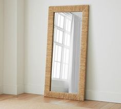 a large mirror sitting on top of a wooden floor next to a white wall in an empty room