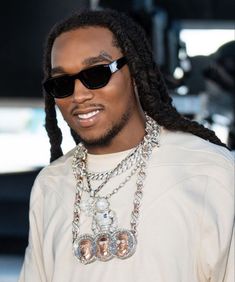 a close up of a person wearing sunglasses and a necklace with chains around his neck