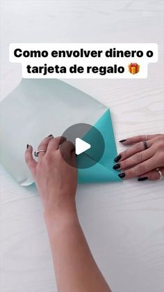 a woman is making a paper boat with her hands on the table and another person's hand reaching for it