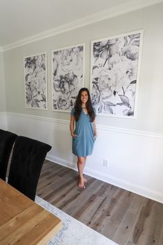 a woman standing in front of three paintings on the wall