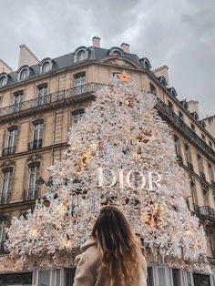 a woman standing in front of a christmas tree