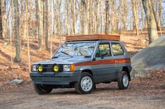 an old car with a basket on top parked in the woods