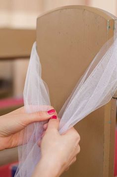 a woman is wrapping up a cardboard box with white netting on it's sides