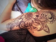 a woman laying on top of a bed with her arm covered in henna tattoos