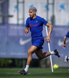 a soccer player running with the ball in his hand and two other players behind him