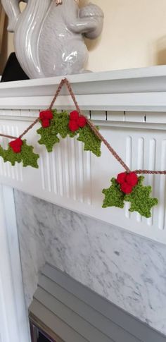 a fireplace mantel decorated with holly and red poinsettis on twine