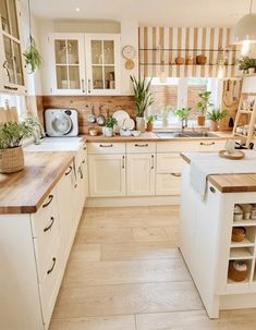 a kitchen filled with lots of white cabinets and wooden counter top space next to a window