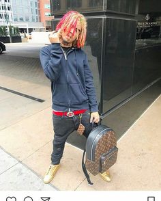 a man with dreadlocks is holding a suitcase and talking on the phone while standing in front of a building