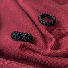 two black hair ties sitting on top of a red cloth