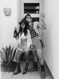 two people dressed up in costumes posing for a photo with one holding a cup and the other wearing an american flag