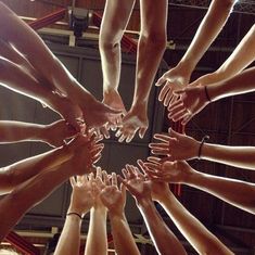 a group of people's hands in the middle of a circle with their fingers together